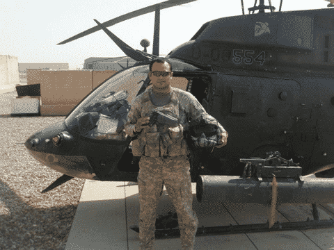 Brandon in his US Army uniform in front of a helicopter